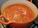 Canned tomatoes and canned, unflavored tomato sauce have been added and are ready to begin cooking, along with a little red wine.